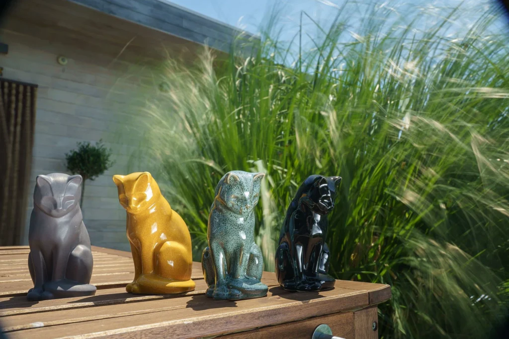 Colorful cat decorative statues displayed on a wooden table outdoors