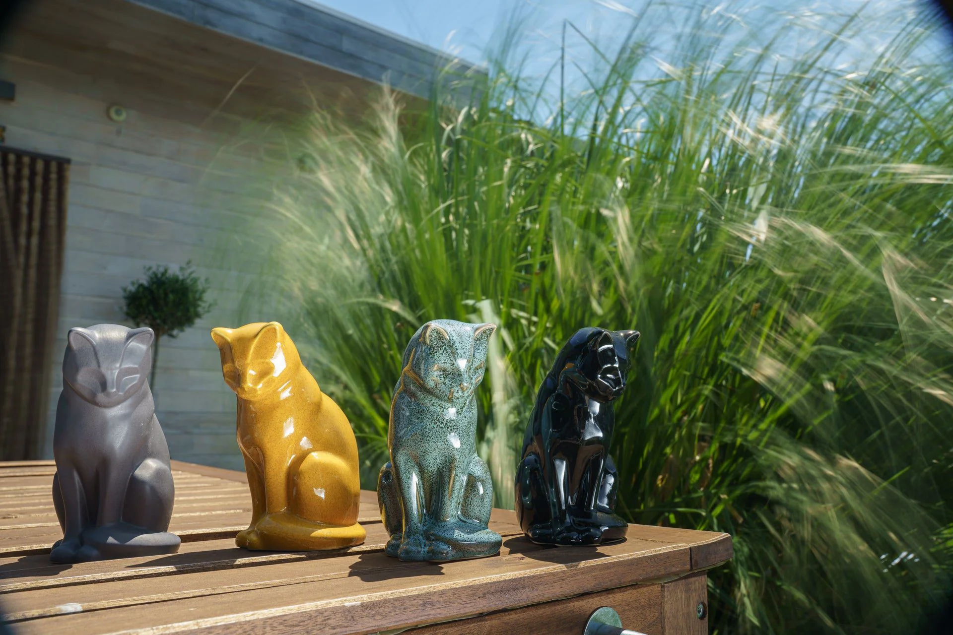 Colorful cat decorative statues displayed on a wooden table outdoors