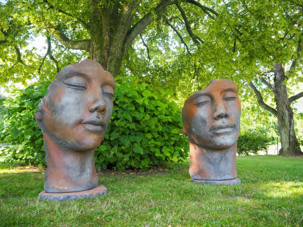 Abstract outdoor head sculptures displayed on a lawn