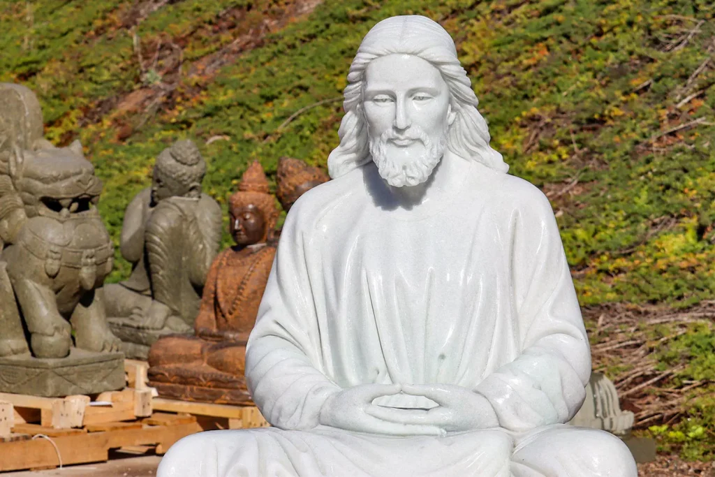 A white marble statue of Jesus seated with folded hands
