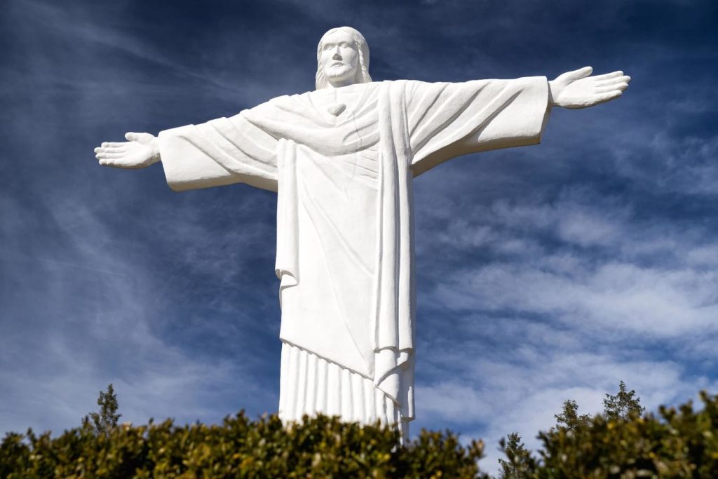 A large white statue of Jesus with open arms